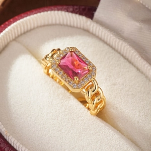 Macro shot of a luxury gold ring with a pink rectangle gemstone and Cuban link band