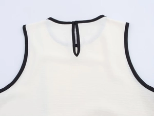 Detail of white sleeveless top neckline with black trim and back teardrop button closure
