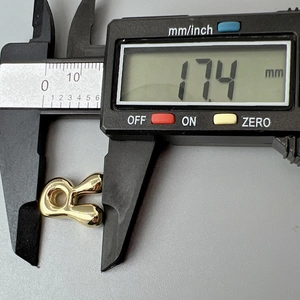 Digital caliper measuring the 17.4 mm length of a polished gold letter necklace pendant
