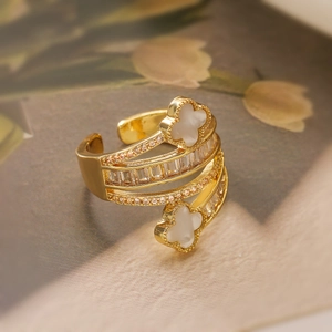 Detailed macro of a 18K gold-plated clover ring featuring white inlay and zircon accents