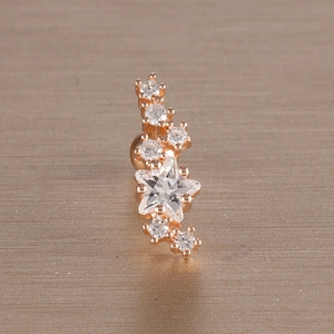 Macro detail of rose gold cartilage earring featuring a star design with clear zircons