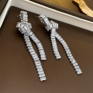 Detailed view of silver knot earrings with zircon fringes and dangling rectangular stones