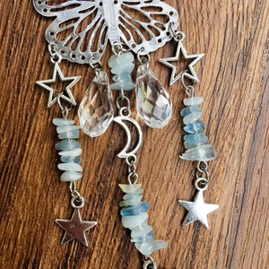 Detail of silver butterfly suncatcher with crystal pendants on a dark wooden surface