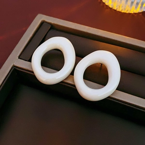 Macro shot of white irregular oval resin earrings on a vintage brown jewelry tray