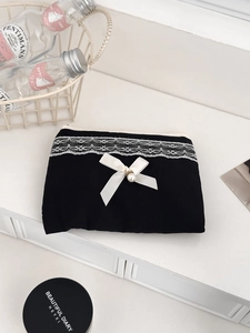 Detail of black fabric coin purse with white lace trim, ribbon bow, and pearl accent