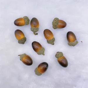 Set of 10 realistic artificial acorns with textured caps on a white plush background