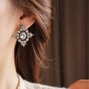 Dettaglio di orecchini vintage a rombo con strass scintillanti indossati da una modella