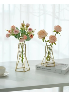 Detail of Nordic geometric gold frame glass vase with pink silk rose on desk