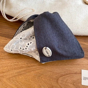 Détail du denim bleu foncé avec broderie en dentelle blanche et logo de marque JUEDE