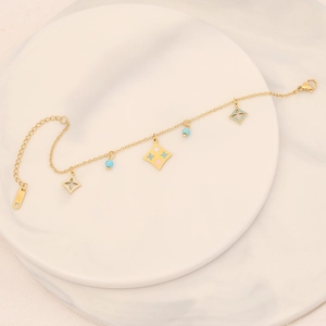 Detail of gold-plated chain with blue beads and enamel flower charm on marble surface
