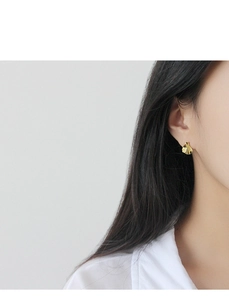 Gros plan de boucles d'oreilles dorées aux formes ondulées et à la finition polie