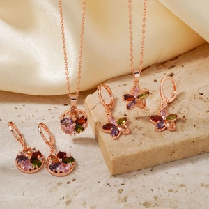Détail de parure de bijoux or rose avec fleurs en gemmes colorées sur soie et pierre