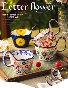 Detail of hand-painted Polish style ceramic mug with floral pattern and wavy rim