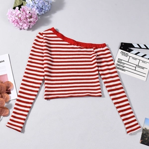 Detailed view of red and white striped knit crop top with off-shoulder design on grey background