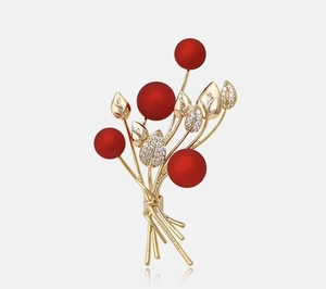 Detail of elegant red berry floral brooch with gold stems and sparkling zircon leaves