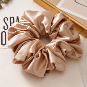 Close-up of elegant champagne gold satin hair scrunchie with smooth silk texture
