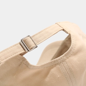 Detail of beige cotton baseball cap featuring an adjustable metal buckle strap