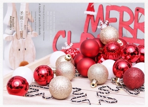 Close-up of red and gold Christmas ornaments set on a rustic wooden tray with warm lights