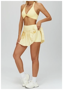 Detailed side view of light yellow pleated sports skirt and twist-knot halter top