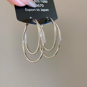 Close-up of double-layer silver earrings with matte and polished finishes on display