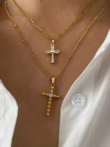 Close-up of layered gold cross necklaces with zircon stones on female model with white shirt