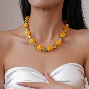 Close-up of yellow acrylic and gold beads necklace on model's neck with vibrant contrast
