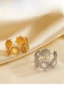 Detail view of 18K gold and silver sun pattern rings on champagne silk fabric