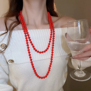 Close-up of elegant double-layered red faux pearl necklace worn by a fashion model