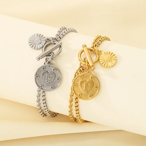 Close-up of gold and silver layered link bracelets with T-bar clasp and heart charm