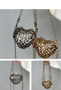 Detail view of heart-shaped hollow metal bags in gold and silver with ball chains