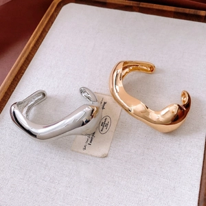 Detailed view of irregular fluid gold and silver bangles with high gloss finish on linen