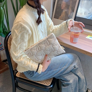 Detailed view of quilted rabbit makeup bag with zipper and logo tag in cafe setting