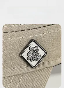 Macro view of khaki twill cotton fabric and silver Fu character badge on the flat top cap