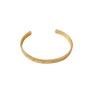 Bracelet jonc ouvert plaqué or avec motifs d'étoiles et zircons sur fond blanc