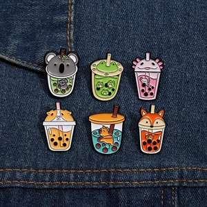 Macro view of six cute animal-themed enamel pins on blue denim fabric background