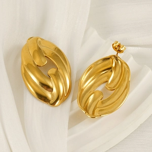Close-up of golden oval chain link earrings on white silk fabric background