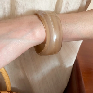 Detail of wide resin bangle with beige marble texture and smooth thick rounded edges