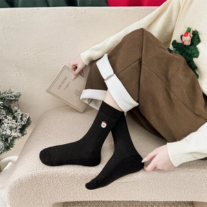 Dettaglio calzini natalizi neri in cotone con ricamo Babbo Natale e maglia