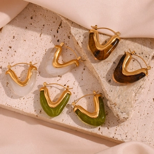 Artistic detail of gold geometric earrings with colorful resin on beige stones