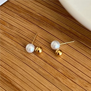 Detail of 925 sterling silver earrings with white pearls and gold metal beads on wood