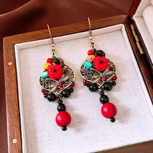 Close-up of vintage resin flower and bronze dragonfly drop earrings on a wood box