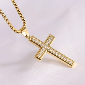 Detailed close-up of a gold-plated cross pendant with sparkling inlaid rhinestones