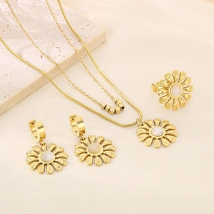 Detail of gold petal jewelry set with pearls on necklace, earrings, and ring