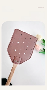 Macro view of a pink leather flyswatter with a long beech wood handle and star cutouts