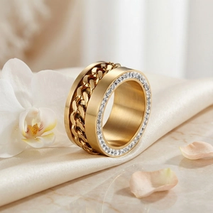 Dettaglio dell'anello largo dorato con cristalli laterali su tessuto di seta color champagne