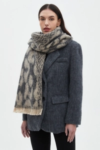 Close-up of grey leopard print scarf with fringe edges worn over a dark grey blazer