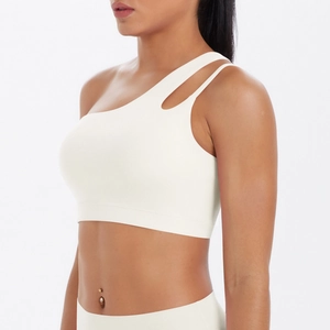 Detailed view of cream one-shoulder yoga bra with cutout strap and elastic underband