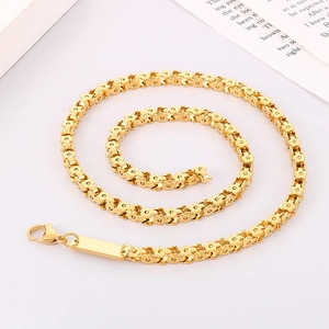 Dettaglio della collana dorata con maglie a fiore e chiusura a moschettone