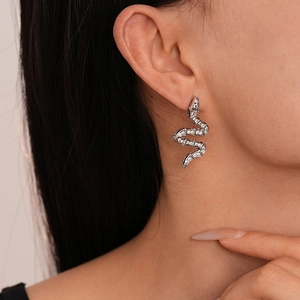 Close-up of a silver snake-shaped earring with white zircons worn by a model