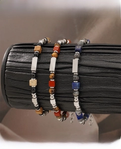 Detail of natural stone beaded bracelets on black leather display showing metal accents